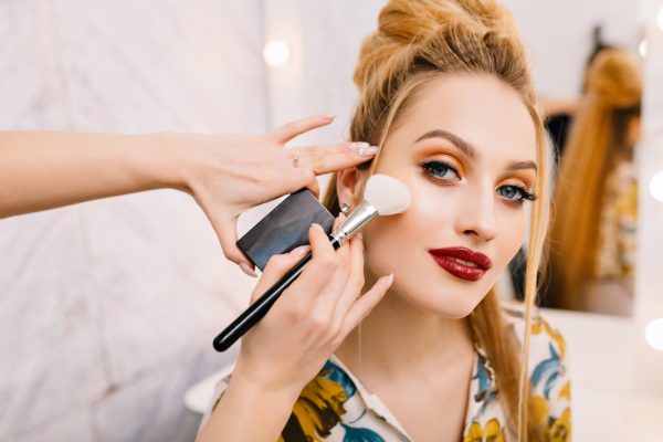 Preparing to party, carnival, celebration of attractive young women in beauty salon. Making makeup, stylish coiffure, professional stylist, cheerful mood, fashionable model.